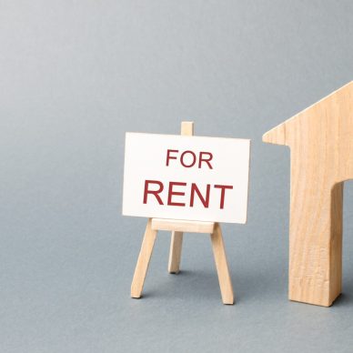 Wooden house and a poster with the inscription for rent. The concept of renting a house or apartment for rent. Affordable housing for young couples or families. Rent a property. Real estate