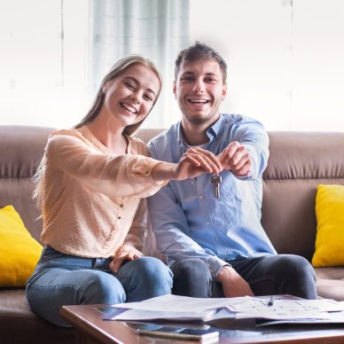 Lovely young girl with her boyfriend showing key to their new property indoors, panorama