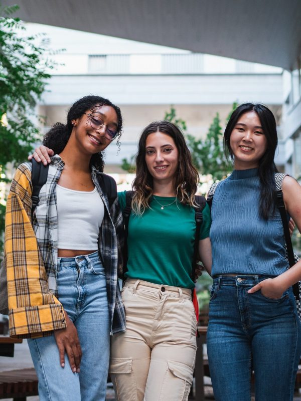 Portrait of three college student girls looking at camera. They are at the university.